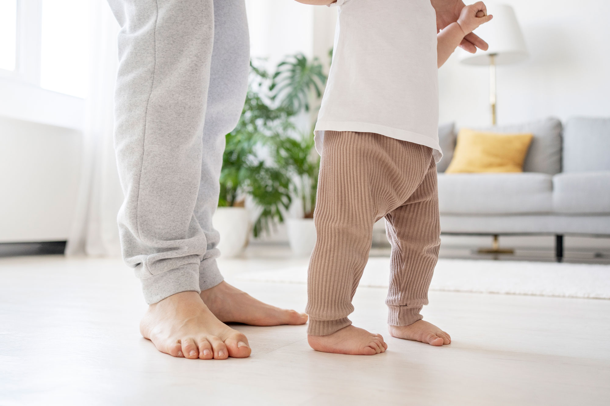 A toddler taking first steps next to a parent