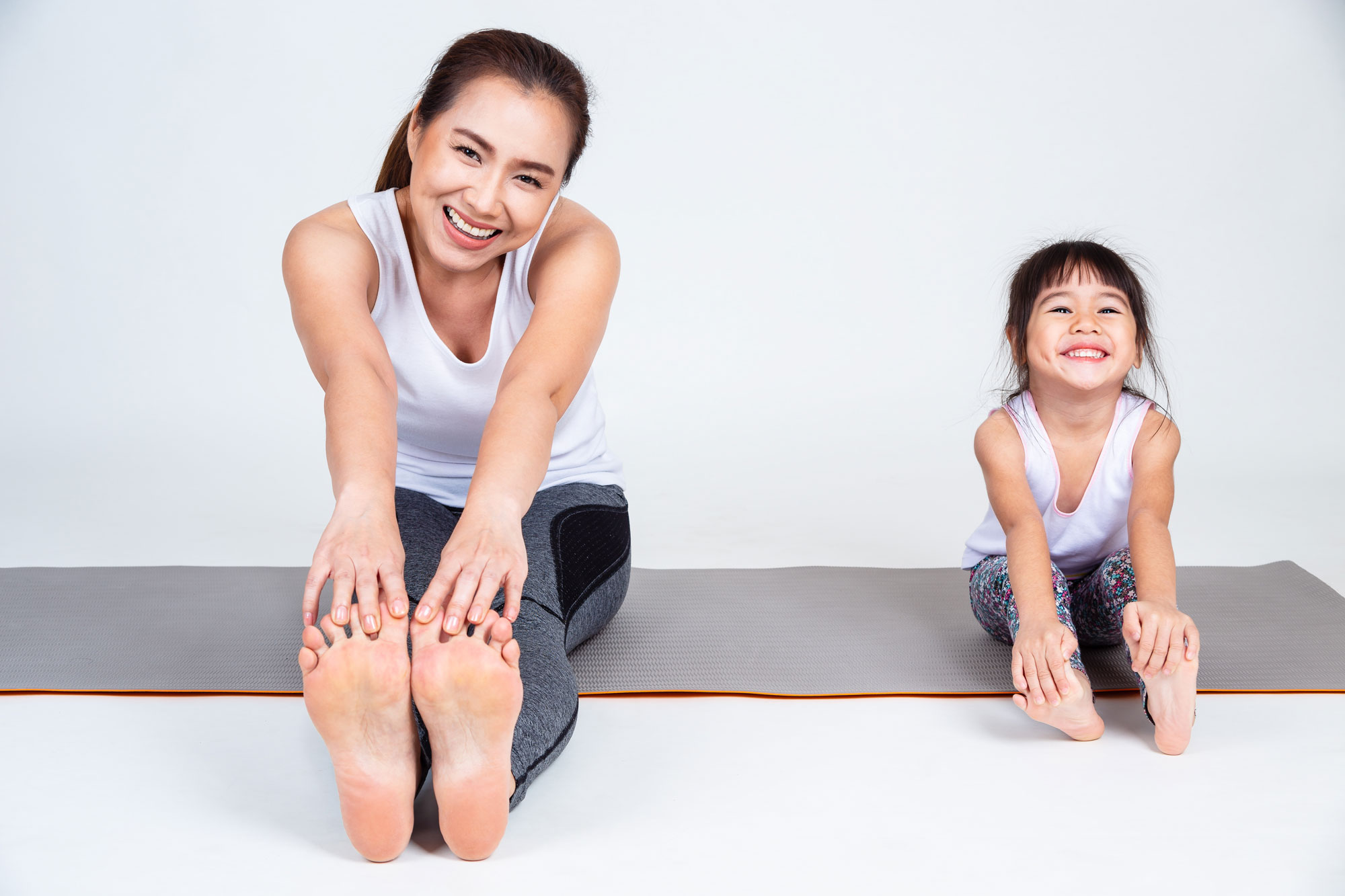 An Asian mother and daughter stretching together